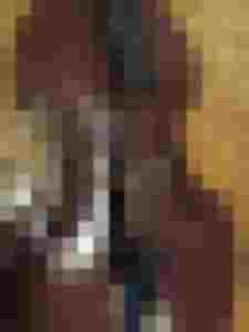 Riss in einem Streichinstrument mit Saiten, umgeben von Holzmaserung und Bodenbelag.