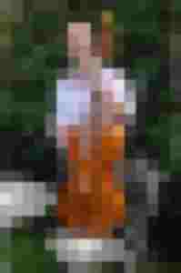 Lächelnde Frau mit einer Holzlaute, umgeben von grünem Garten und Gartenmöbeln.