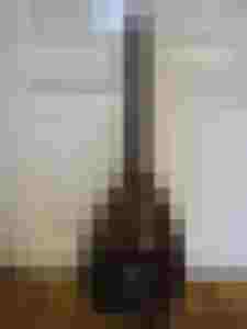 Holz-Saiteninstrument mit glänzender Oberfläche vor einer weißen Wand.